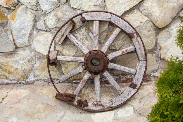 Vecchia rotella di metallo e di legno sul fondo del muro di pietra