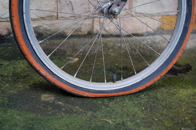 Vecchia ruota di bicicletta con la gomma a terra sulla strada sporca