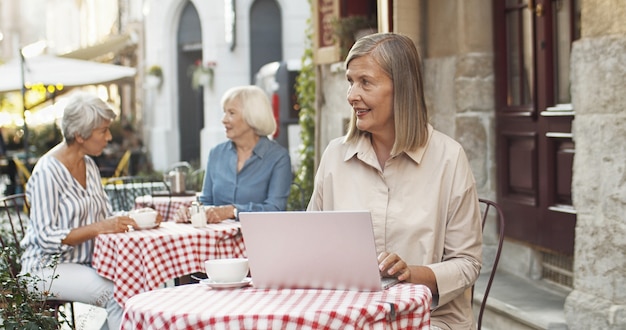 Vecchia scrittrice che manda un sms sulla tastiera sulla terrazza