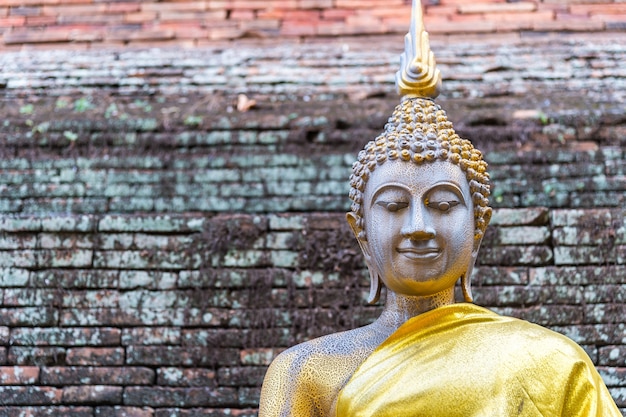 Vecchia statua di Buddha con il fondo del muro di mattoni