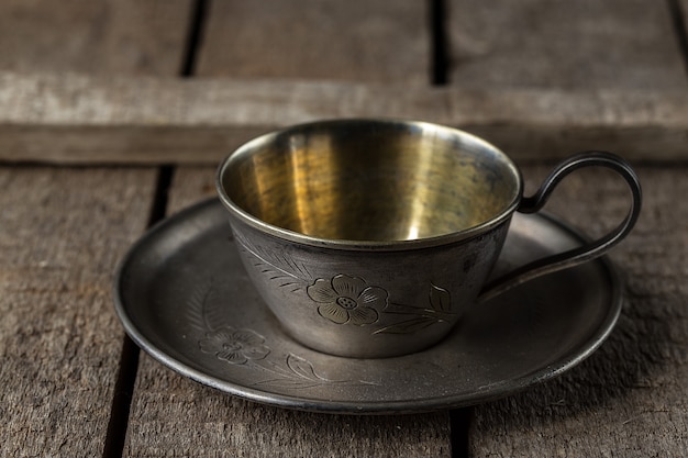 Vecchia tazza di metallo per caffè su un piattino