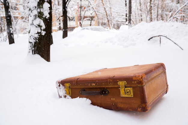 Vecchia valigia marrone in pelle nella neve