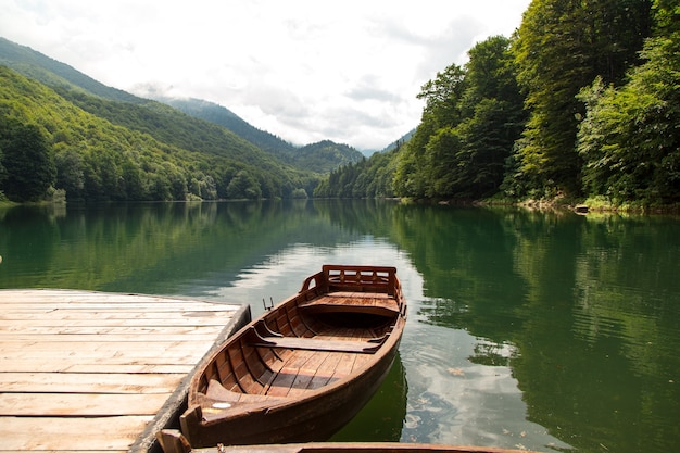 Vecchie barche di legno sono sul molo, su un bellissimo lago di montagna.