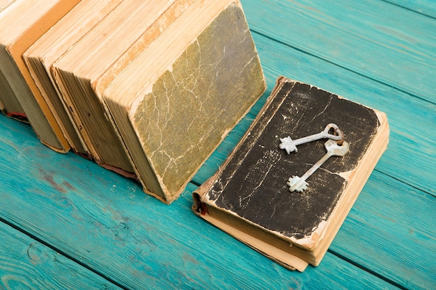 Vecchie chiavi su un vecchio libro e pila di libri antichi sullo scrittorio di legno blu