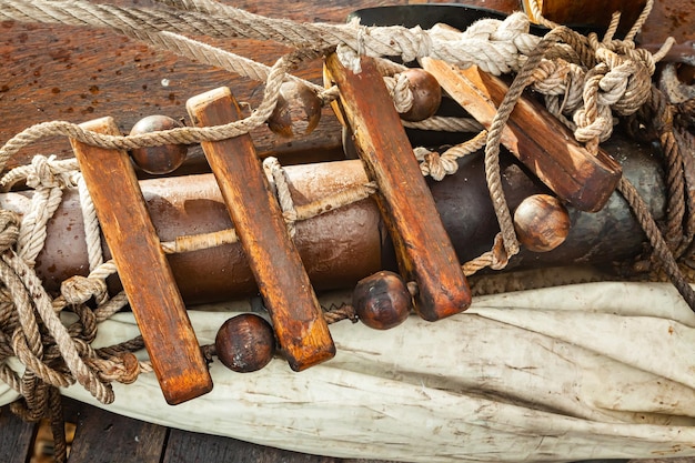 Vecchie corde una vela ripiegata e una scala di corda sul ponte di legno di un vecchio primo piano della nave