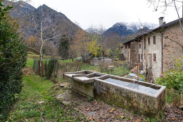 Vecchie fontane in un villaggio delle alpi italiane in autunno