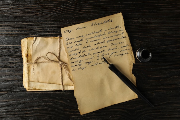 Vecchie lettere lettera con testo e penna su sfondo di legno vista dall'alto