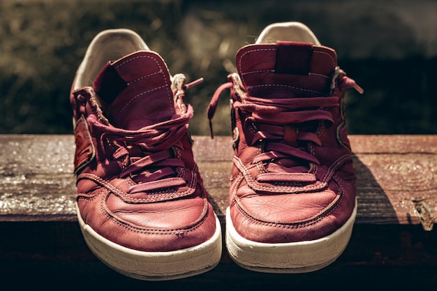 Vecchie scarpe da ginnastica marrone rossiccio su un fondo astratto di legno