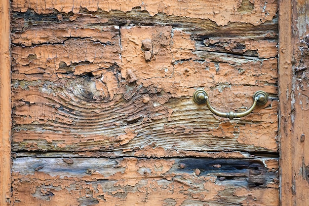 Vecchio battitore della maniglia di porta del metallo su un fondo di legno ruvido
