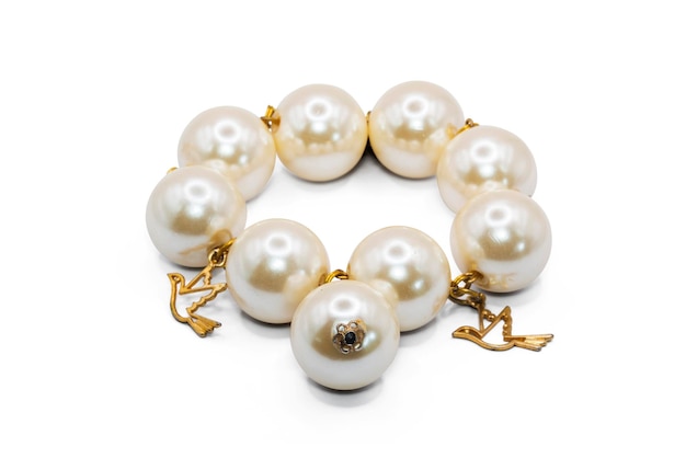 vecchio bracciale rigido realizzato in plastica color perla e metallo dorato isolato su sfondo biancoperla e colore orovintage e retrofoto macroha percorso