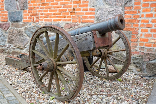 vecchio cannone di fronte a un muro di mattoni