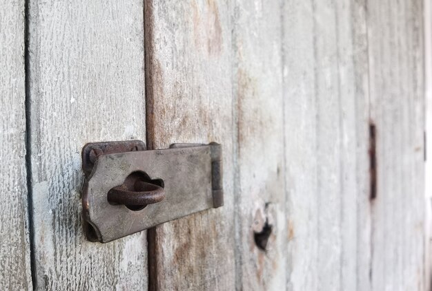 Vecchio cardine arrugginito sulla vecchia porta di legno C'è un'area a destra per l'inserimento di testo. Messa a fuoco selettiva.