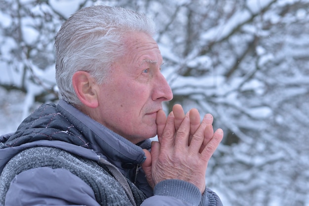 Vecchio che prega Dio con la mano incrociata in inverno nevoso