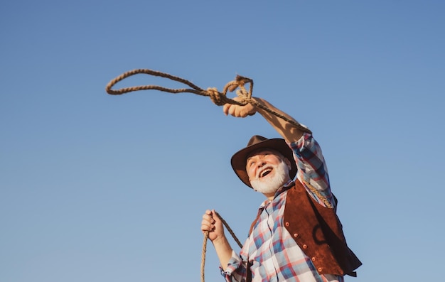 Vecchio cowboy occidentale con corda di lazo Uomo del selvaggio west barbuto con giacca e cappello marroni