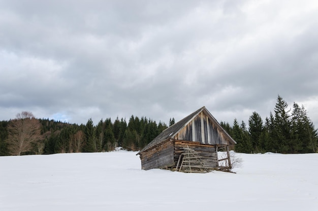 Vecchio edificio in legno decrepito in montagne innevate