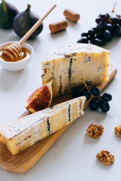 Vecchio formaggio inglese Stilton. Formaggio blu, fichi e uva su un tagliere di marmo