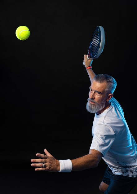 Vecchio giocatore di padel tennis con la racchetta in azione atleta con la racchetta da paddle tennis in campo con