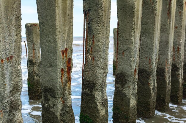 Vecchio groyne fatto di primo piano di pali di cemento sullo sfondo di un mare in tempesta