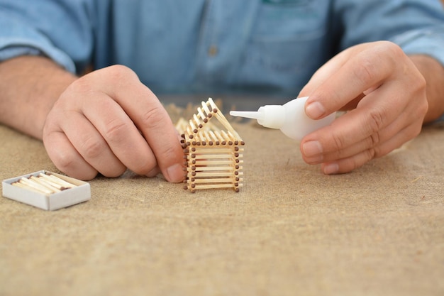 Vecchio impegnato in lavori manuali colla casa con fiammiferi Costruire sogni Fatto a mano Posto libero Ricamo Hobby