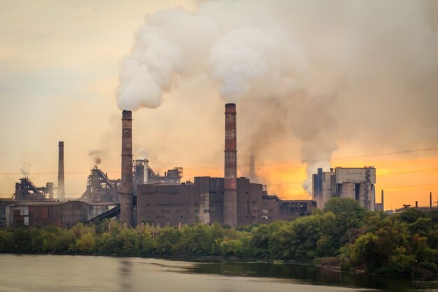 Vecchio impianto, posto sull'argine della città, con ciminiere che soffiano fumo nell'atmosfera all'alba