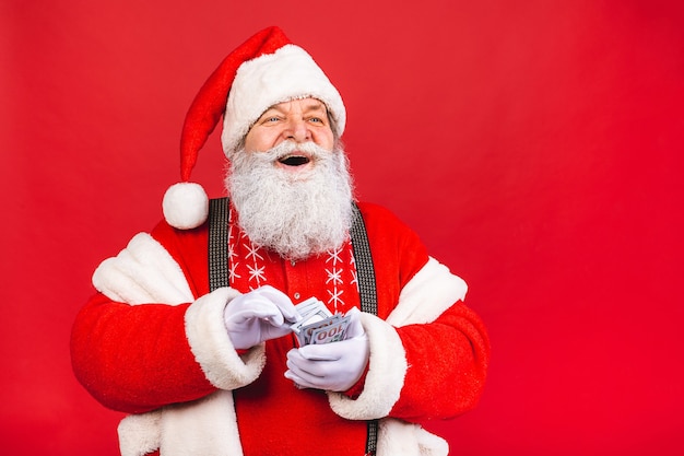 vecchio in costume di Babbo Natale che conta soldi isolato su sfondo rosso