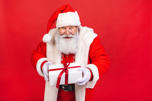 vecchio in costume di Babbo Natale in possesso di un presente isolato su sfondo rosso