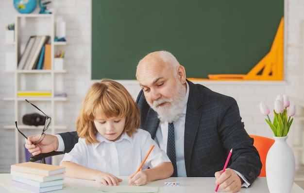 Vecchio insegnante e giovane scolaro che fanno i compiti a scuola Giornata degli insegnanti