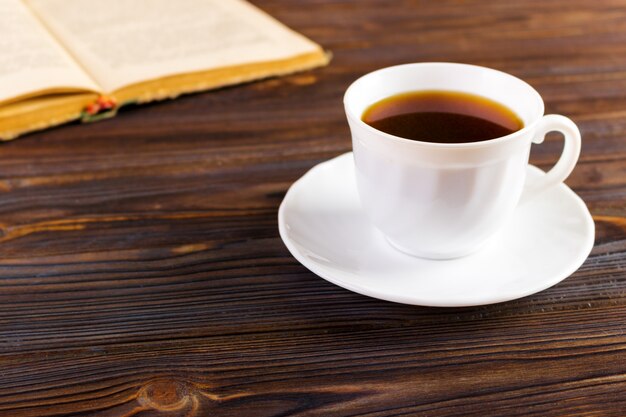 Vecchio libro e una tazza di caffè su un fondo di legno, immagine tonificata