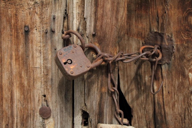 Vecchio lucchetto arrugginito con catena sulla porta di legno