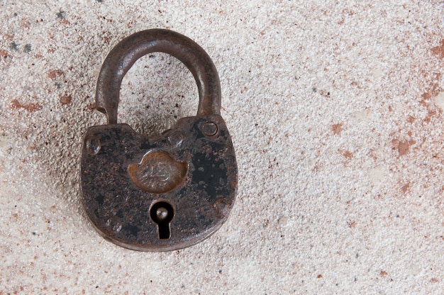 Vecchio lucchetto arrugginito del ferro su fondo concreto.