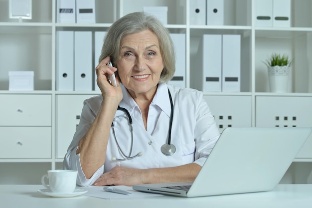 Vecchio medico con un computer portatile funzionante