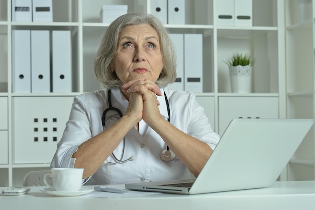 Vecchio medico con un computer portatile funzionante