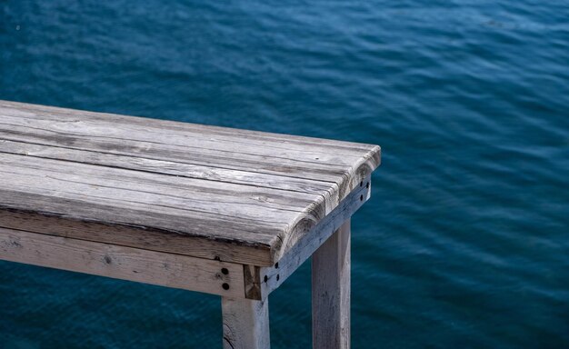 Vecchio molo di panca in legno su sfondo blu del mare