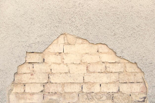 Vecchio muro di mattoni con un intonaco rotto