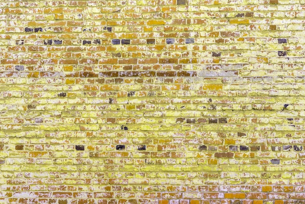 Vecchio muro di mattoni gialli Peeling vernice bianca su una parete gialla
