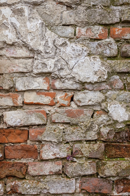 Vecchio muro di mattoni stagionato. Muro di mattoni invecchiato con sfondo di intonaco incrinato