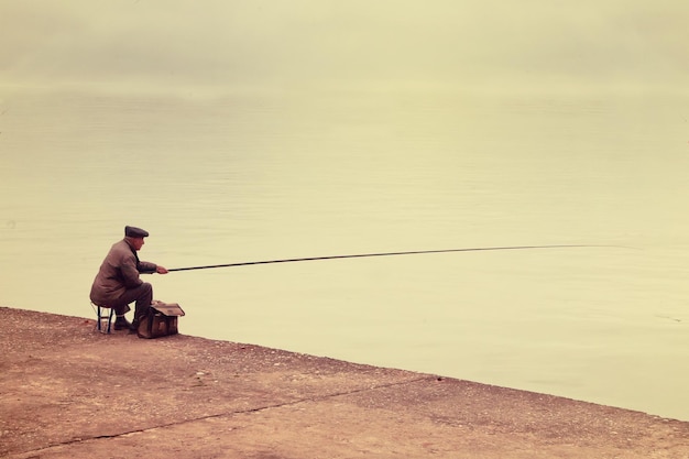 Vecchio pescatore seduto su un molo