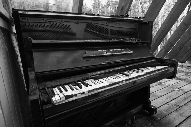 Vecchio pianoforte vintage rotto Nero pianoforte distrutto e dimenticato in un luogo abbandonato in bianco e nero