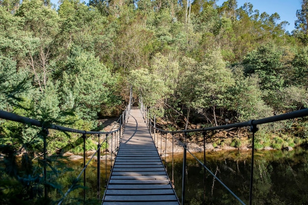 Vecchio ponte sospeso in legno sopra un fiume calmo in Galizia Spagna