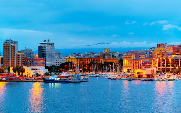 Vecchio porto sardo con navi nel Mar Mediterraneo e città di Cagliari, isola del sud Sardegna in Italia in estate. Paesaggio urbano con porto turistico e yacht e barche in città