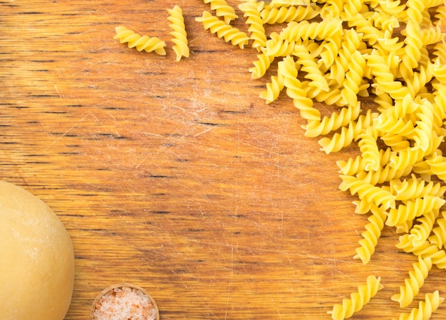 Vecchio tagliere di legno e pasta secca con pasta. Sfondo di gastronomia