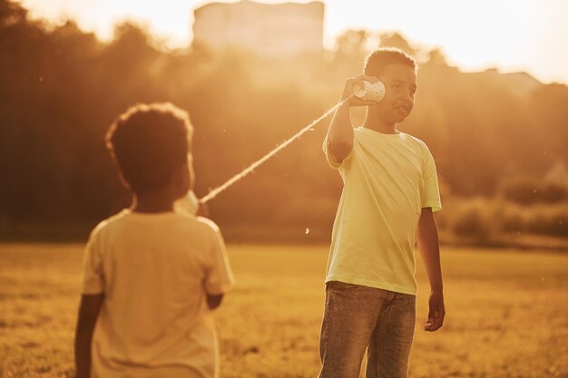 Vecchio telefono giocattolo Due bambini afroamericani si divertono insieme sul campo durante il giorno d'estate