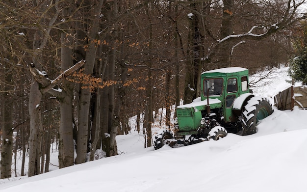 Vecchio trattore rustico verde in tempo nevoso