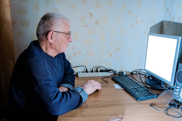 Vecchio uomo maturo anni '80 a casa usando il pc. Pensionamento online, istruzione, shopping, medicine per anziani
