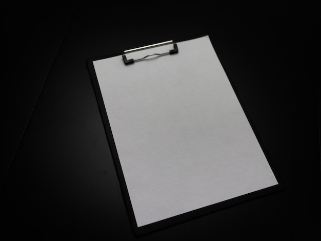 Veduta ad alto angolo di carta bianca sul clipboard su sfondo nero