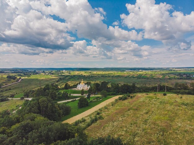 Veduta aerea dei campi della chiesa intorno al cielo blu con nuvole bianche