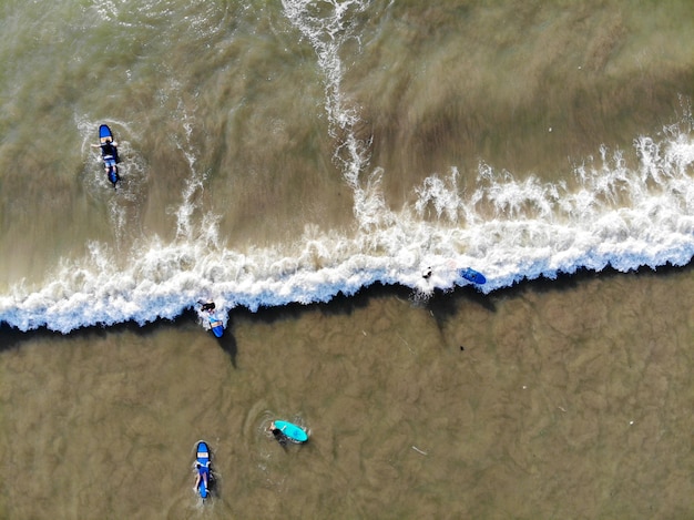 Veduta aerea dei surfisti che aspettano le onde nell'acqua marrone scuro