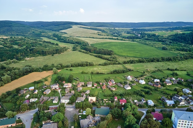 Veduta aerea del paesaggio delle case del villaggio e dei campi coltivati verdi lontani con colture in crescita in una luminosa giornata estiva