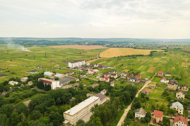 Veduta aerea del paesaggio delle case del villaggio e dei campi coltivati verdi lontani con colture in crescita in una luminosa giornata estiva