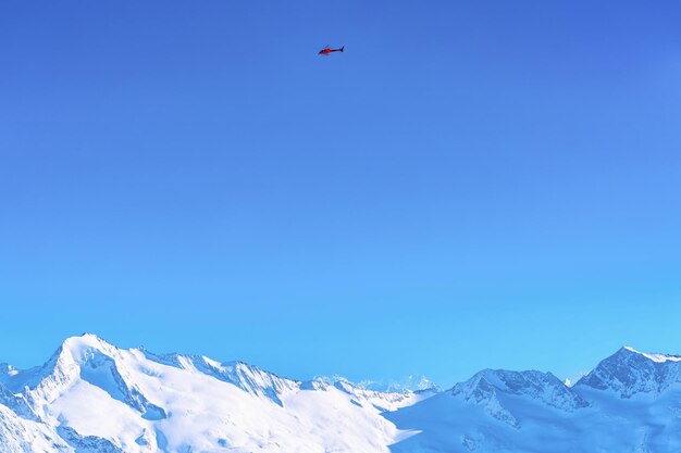 Veduta aerea dell'elicottero che sorvola il ghiacciaio Hintertux in Tirolo a Mayrhofen nella valle Zillertal dell'Austria nelle Alpi invernali. Chopper sopra le cime di Hintertuxer Gletscher nelle montagne alpine. Cielo blu